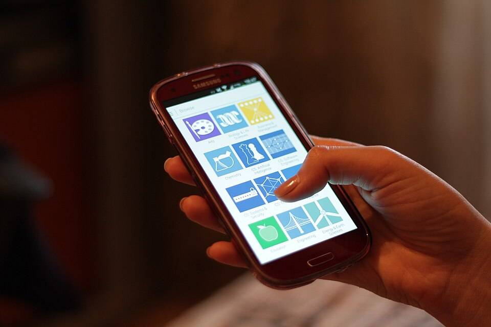 Tangan pengguna memegang ponsel pintar untuk membaca konten